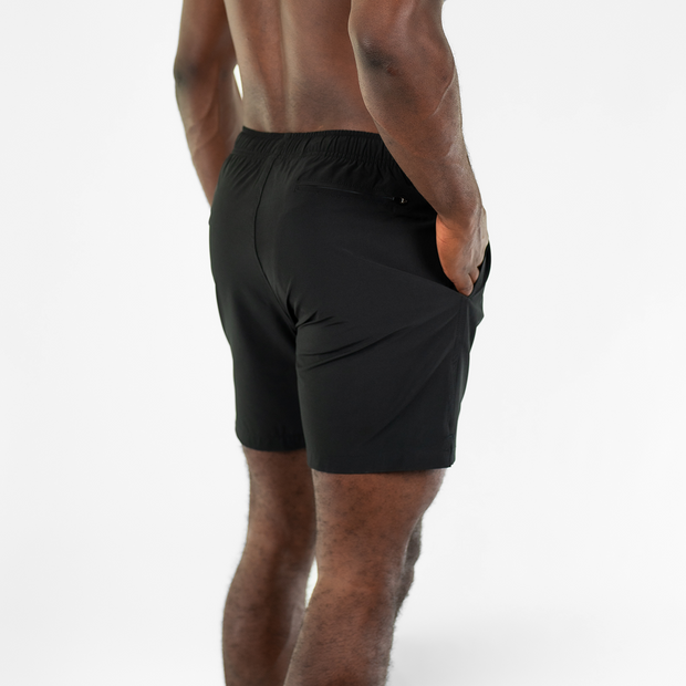Stretch Swim 7" in Black back right angle on model with hands in inseam pockets