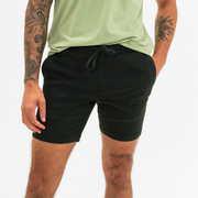 Alto Short 7" inseam in Black front on model with elastic waistband, fabric drawstring, faux fly, and two front side seam pockets