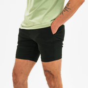 Alto Short 7" inseam in Black side on model with elastic waistband, fabric drawstring, faux fly, and two front side seam pockets