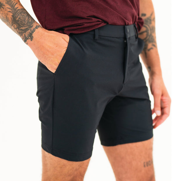 Tour Short 7" Black side on model with flat elastic waistband, belt loops, snap-button, zipper fly, and two front seam pockets