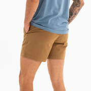 Stretch Short 5.5" Camel back on model with right buttoned back pocket worn with Natural Dye Logo Tee Ocean
