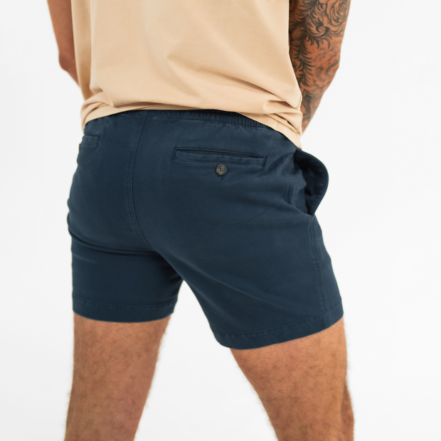 Alto Short 5.5" inseam in Navy back on model with elastic waistband and two welt pocket with horn buttons