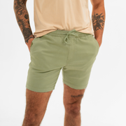 Alto Short 7" inseam in Olive front on model with elastic waistband, fabric drawstring, faux fly, and two front side seam pockets