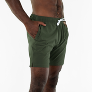 Stretch Swim Solid 7" Military Green on model at 45 degree angle with hand in inseam pocket