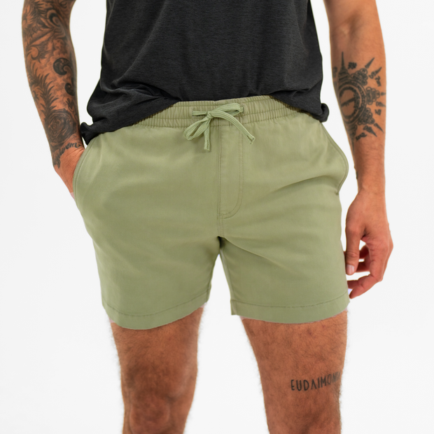 Alto Short 5.5" inseam in Olive front on model with elastic waistband, fabric drawstring, faux fly, and two front side seam pockets